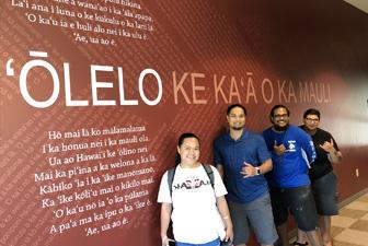 Group of students in front of a mural showcasing words in ‘Olelo Hawaii 