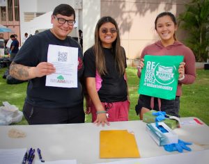 Three students holding sustainability flyers